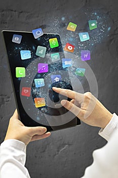 Woman holding a tablet with modern colorful floating apps and icons.