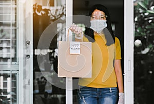 Woman holding takeaway food in paper bag from delivery service during coronavirus pandemic situation at home