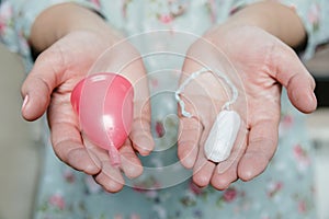 Woman holding tampon and menstrual cup in her hands photo