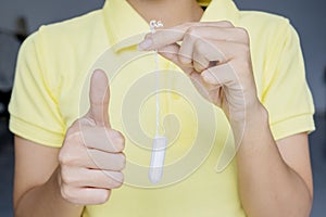 Woman holding tampon and showing thumb up