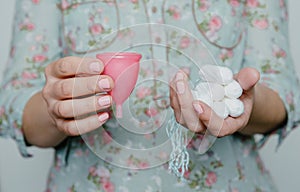 Woman holding tampons and menstrual cup in hands photo