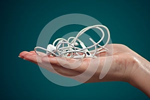 Woman holding tangled earphone trying to untangle it. People and technology concept