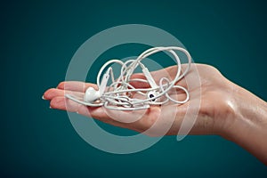 Woman holding tangled earphone trying to untangle it. People and technology concept