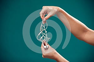 Woman holding tangled earphone trying to untangle it. People and technology concept