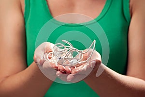 Woman holding tangled earphone trying to untangle it. People and technology concept