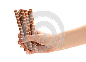 Woman holding tasty wafer roll sticks on white background, closeup.