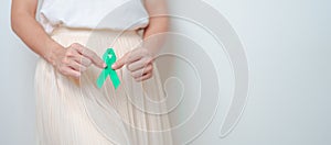 Woman holding Teal Ribbon on abdomen for January Cervical Cancer Awareness month. Uterus and Ovaries, Cervix, Endometriosis,