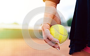 Woman holding tennis ball standing on the court.