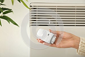 Woman holding thermostat at home. Heating saving concept