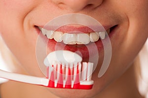 Woman holding toothbrush in front of teeth promoting mouth hygiene for healthy teeth.