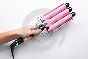 Woman holding triple curling hair iron on white background, closeup