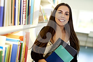 Woman holding two books in library