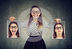 Woman holding two different face emotion masks of herself