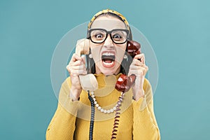 Woman holding two telephone receivers and shouting