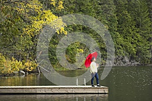 Woman holding umbrella stands on a dock