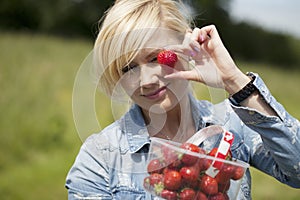 Woman holding up large ripe strawberry