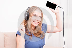 Woman holding up smartphone listening to headphones