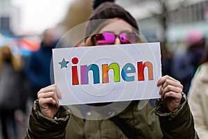 Woman holding up white sign with colorful text saying \