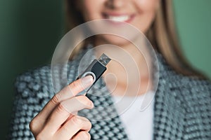 Woman holding usb flash drive against green background, focus on hand