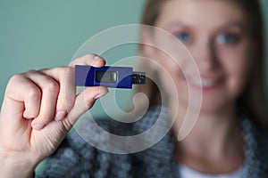 Woman holding usb flash drive against green background, focus on hand