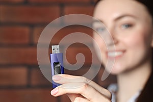 Woman holding usb flash drive near brick wall, focus on hand