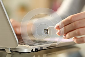 Woman holding usb flash drive next to laptop at home