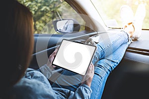 A woman holding and using digital tablet with blank screen in the car