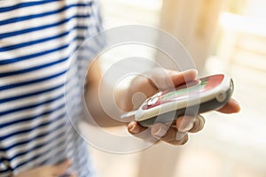 Woman holding and using Glucose meter to check blood sugar level in the bedroom on morning. Use as Medicine, diabetes, glycemia,