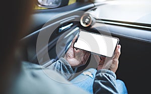 a woman holding and using mobile phone with blank screen in the car