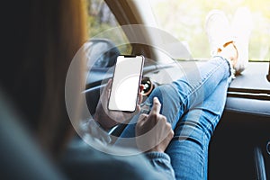 A woman holding and using mobile phone with blank screen in the car