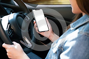 A woman holding and using mobile phone with blank screen while driving car
