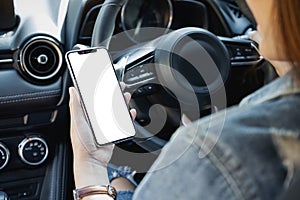 A woman holding and using mobile phone with blank screen while driving car