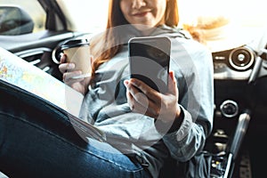 A woman holding and using mobile phone while riding the car