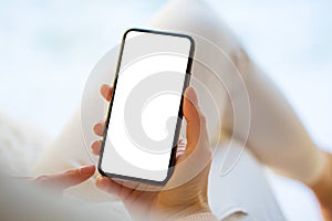 Woman holding and using smartphone at home.