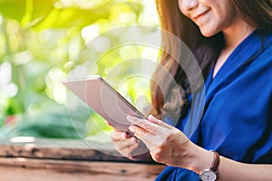 A woman holding and using tablet pc while sitting in the garden