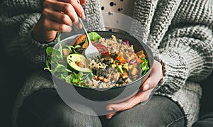 Woman holding a vegetable salad bowl near window light.