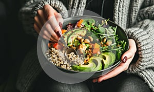 Woman holding a vegetable salad bowl near window light.