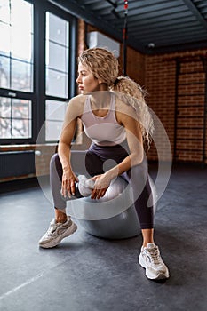 Woman holding water bottle sitting on fitness ball