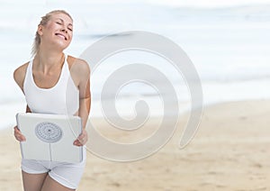Woman holding weighing scale on the beach