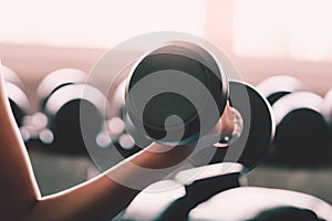 Woman holding weight to train her arm and shoulder muscles in fitness gym