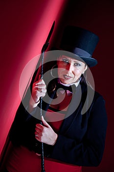 Woman holding whip and wearing top hat