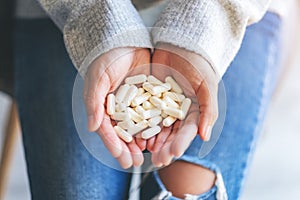 A woman holding white medicine capsules in hand
