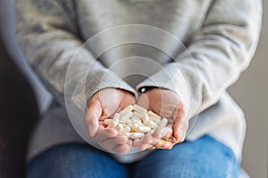 A woman holding white medicine capsules in hand