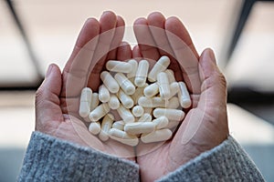 A woman holding white medicine capsules in hand