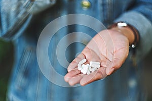 A woman holding white medicine capsules in hand