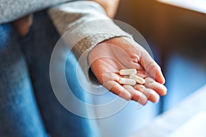 A woman holding white medicine capsules in hand