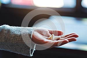 a woman holding white medicine capsules in hand