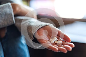 a woman holding white medicine capsules in hand