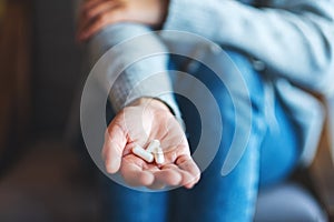 A woman holding white medicine capsules in hand