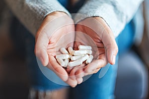 A woman holding white medicine capsules in hands